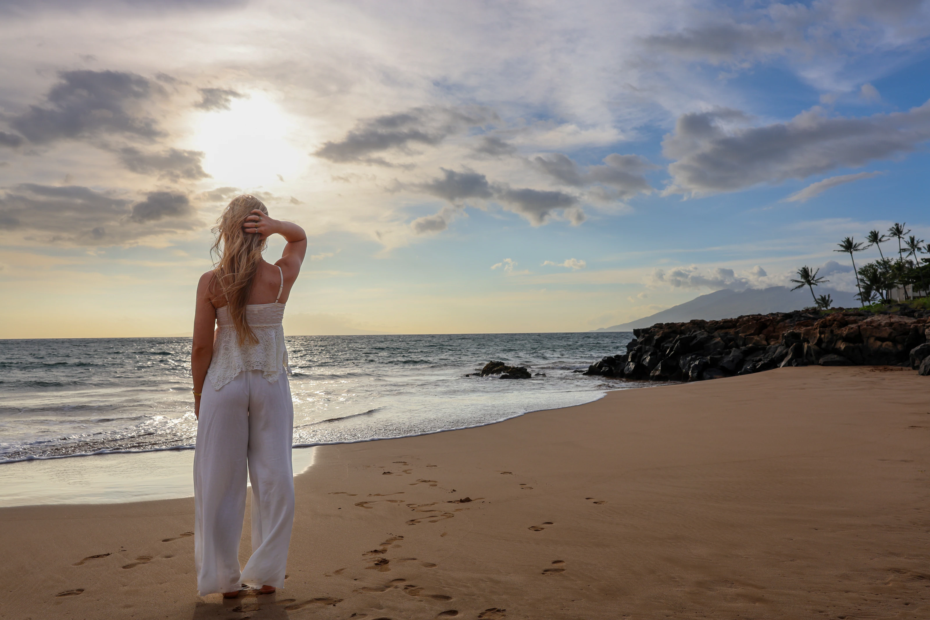Woman in white facing the ocean under a dramatic sky