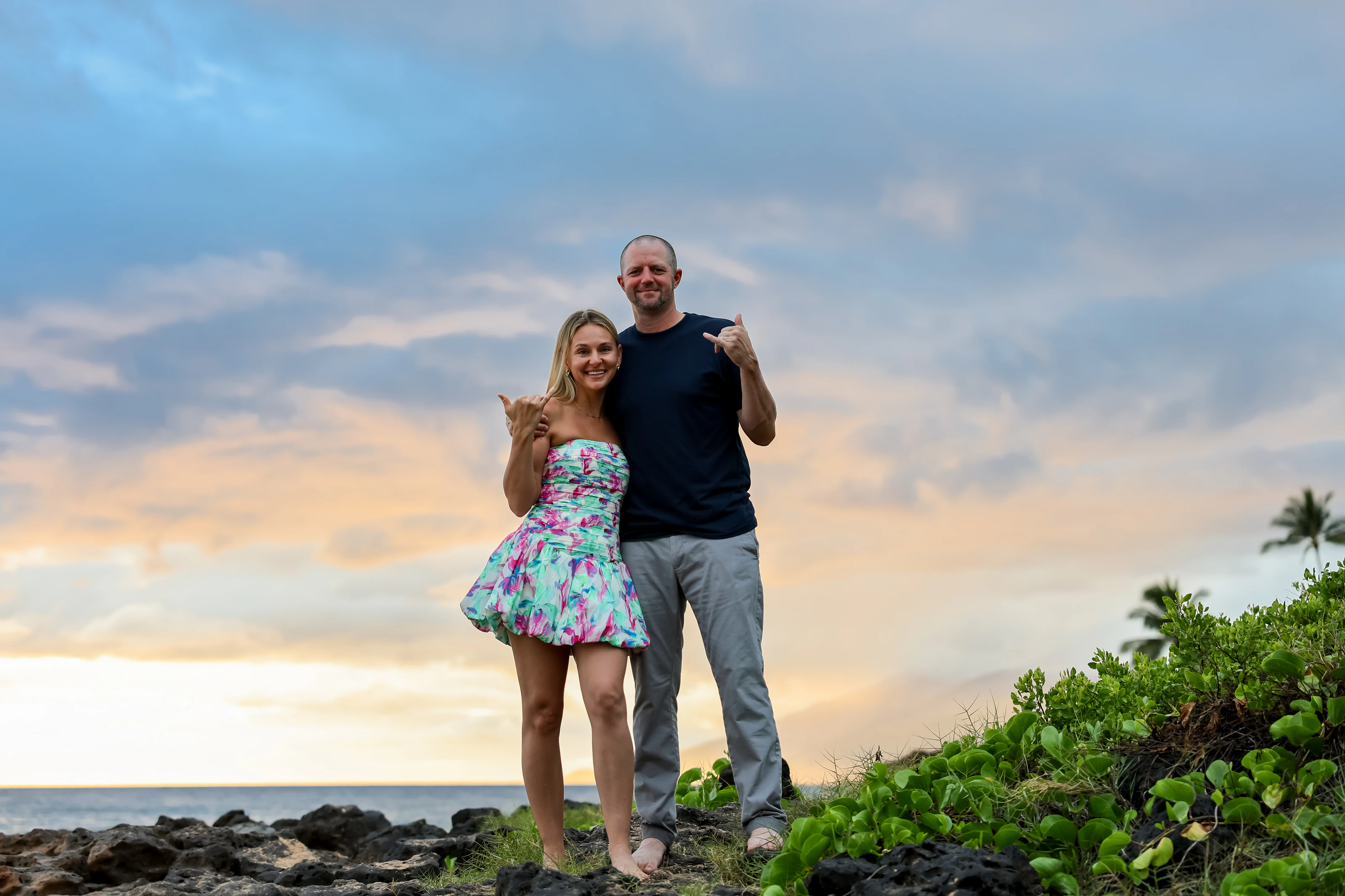 Couple posing casually under a colorful evening sky