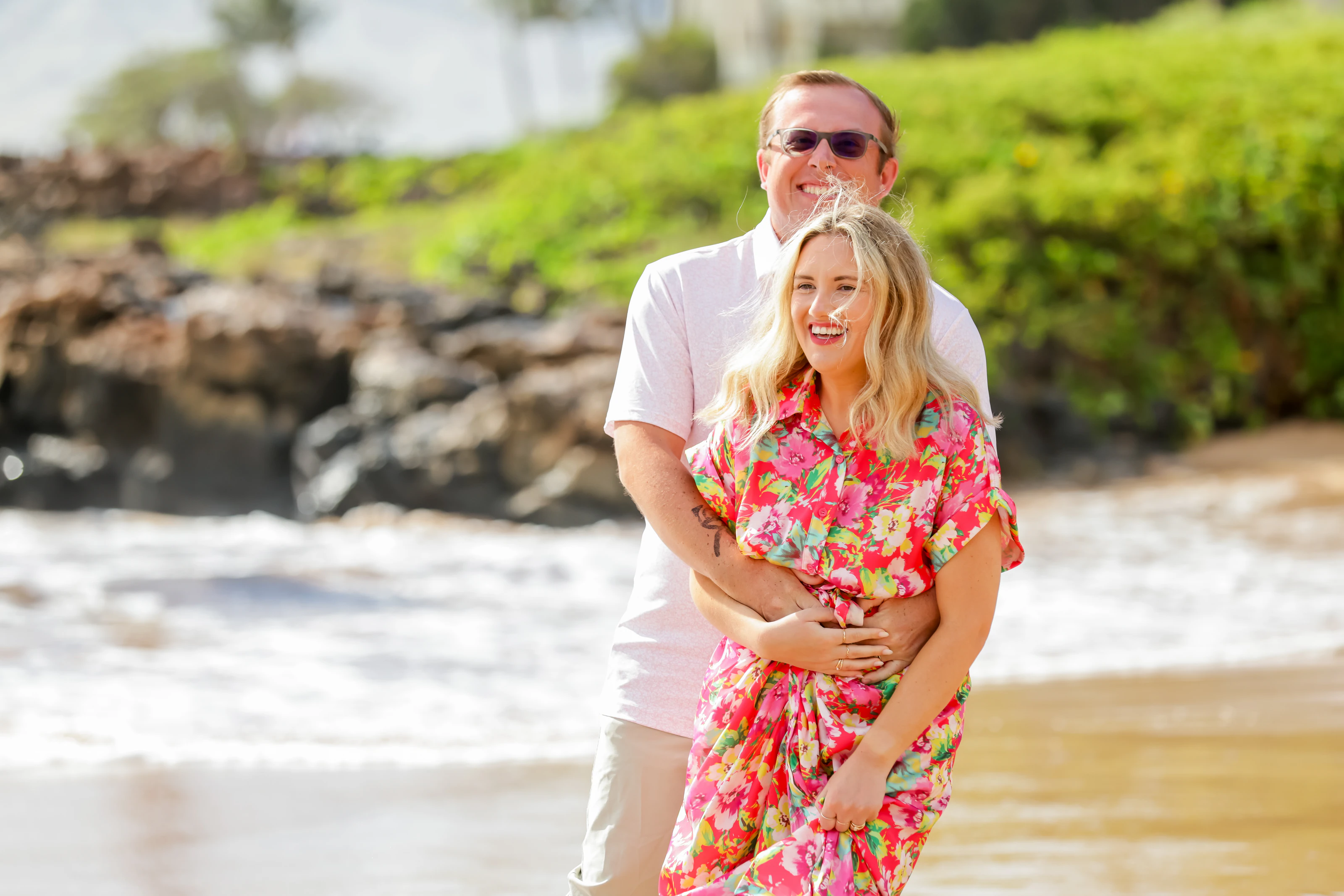 Couple laughing together in bright floral clothing on the beach
