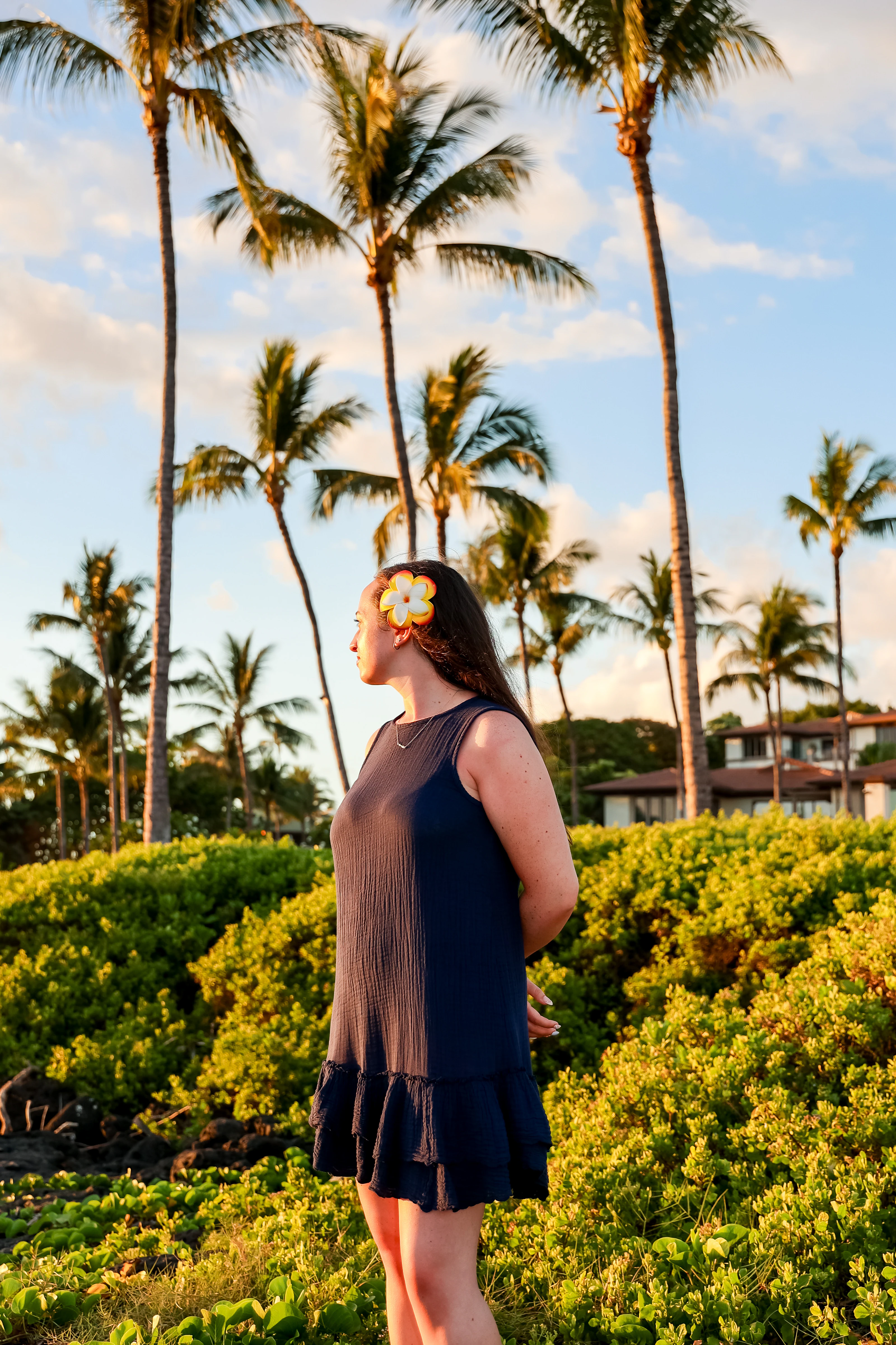Woman in a navy dress among palms at golden hour