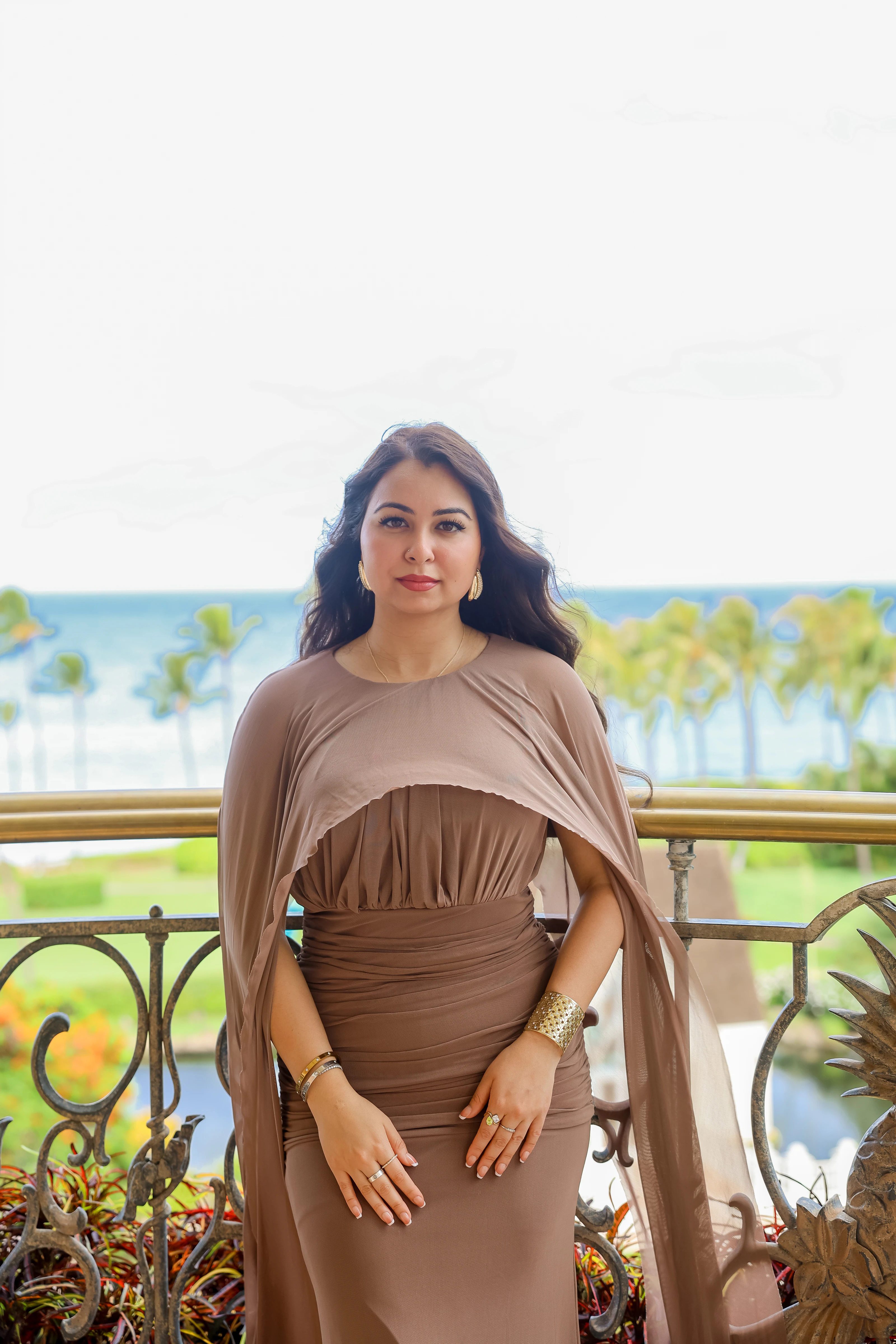Woman in a brown dress seated on a balcony overlooking Maui