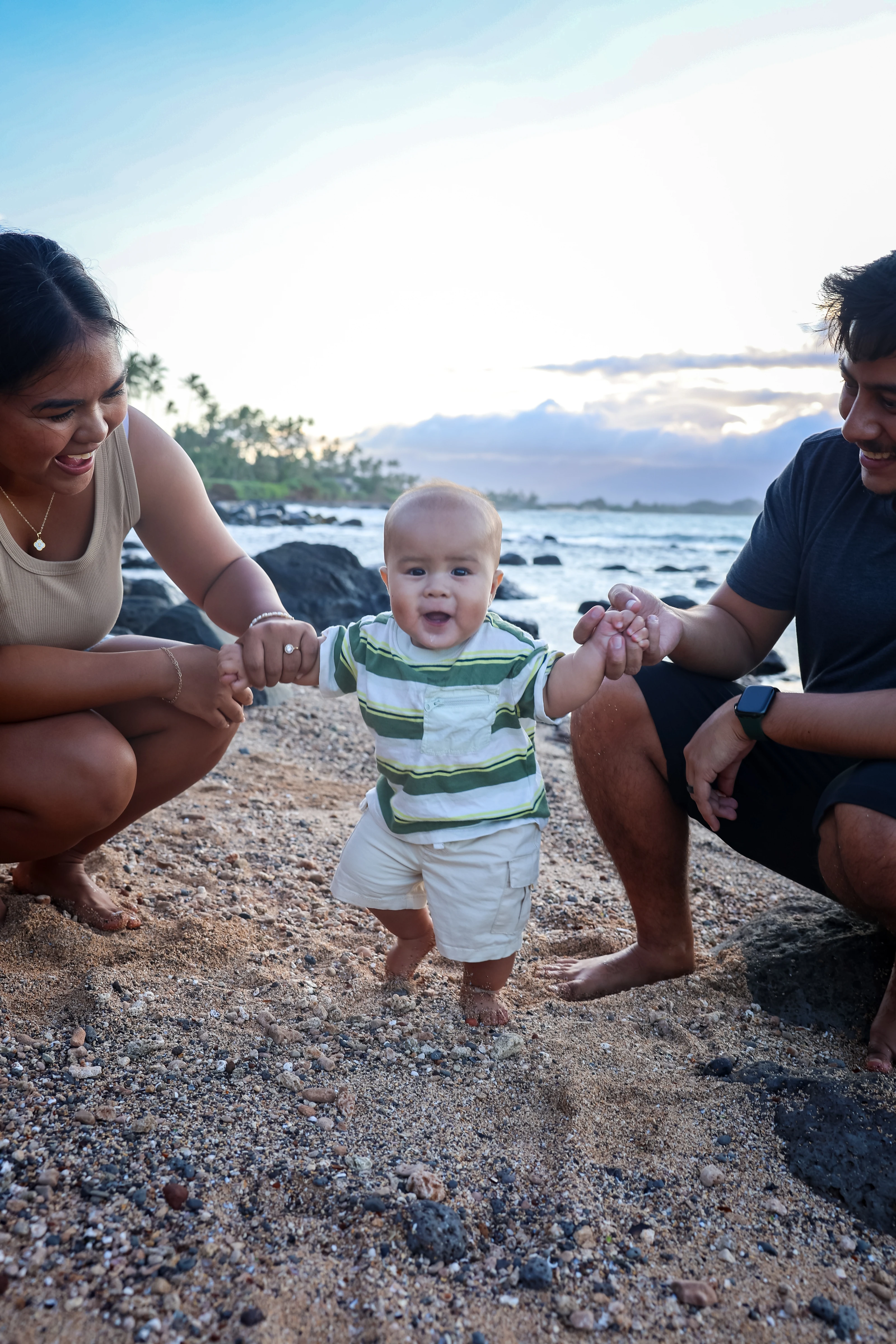 Parents kneeling beside their baby on a Maui beach