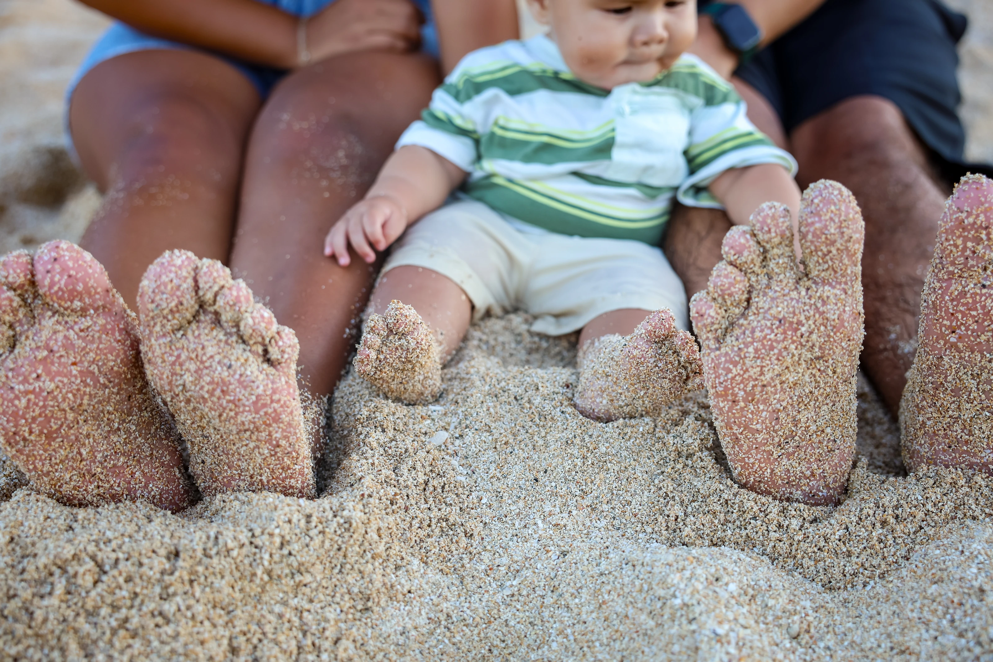 Family sitting together with sandy feet beside the ocean