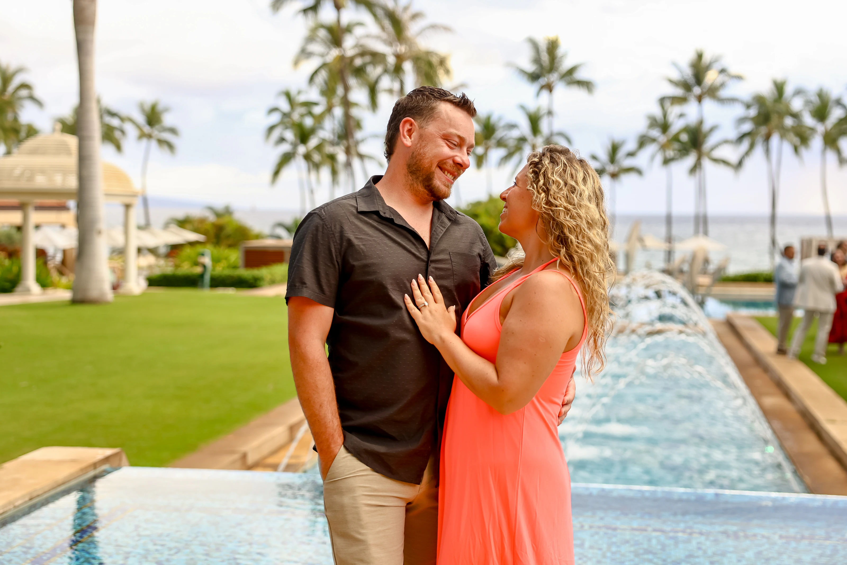Couple smiling together by a resort fountain and palms
