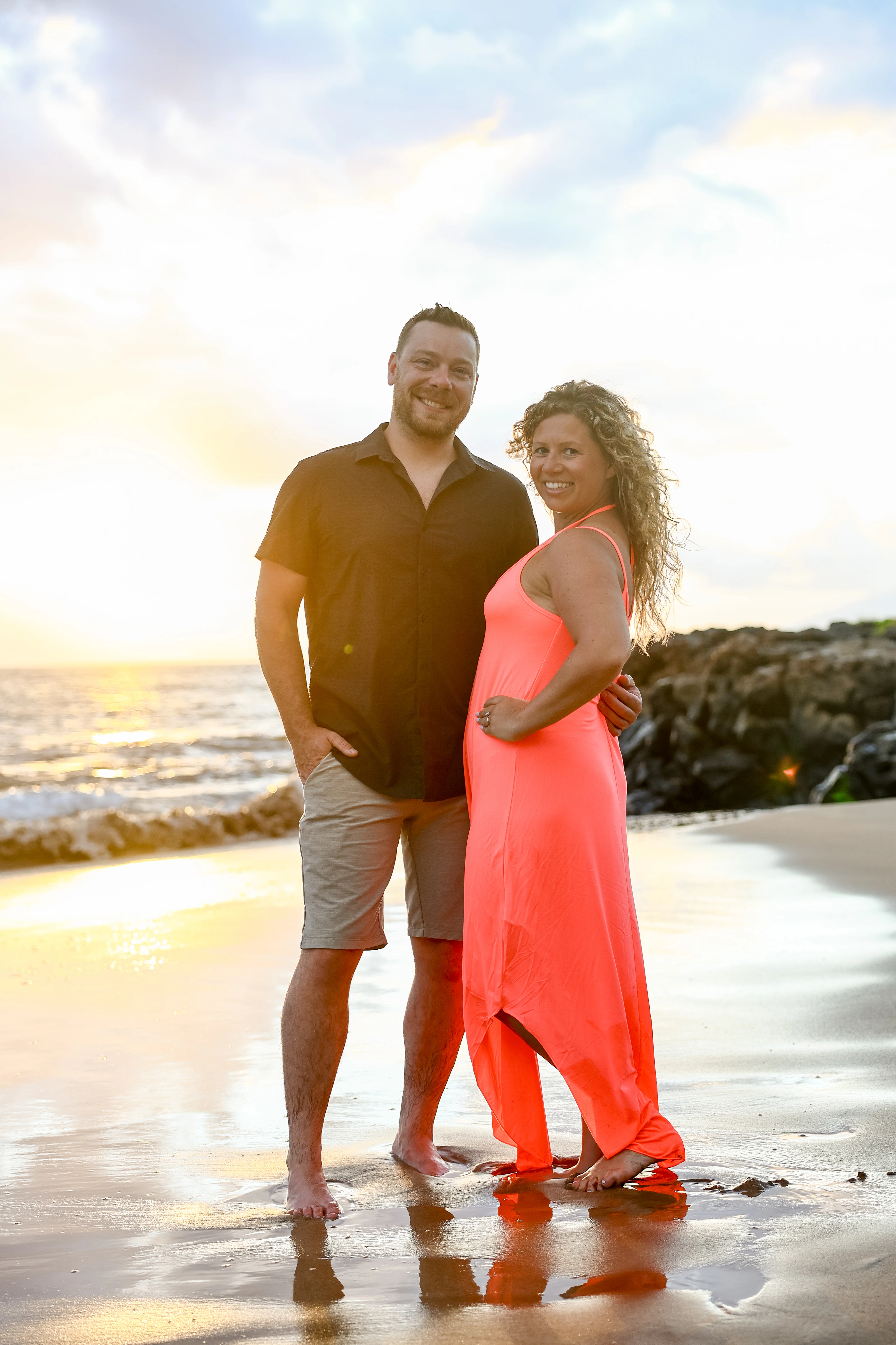 Couple standing together in shallow water at sunset