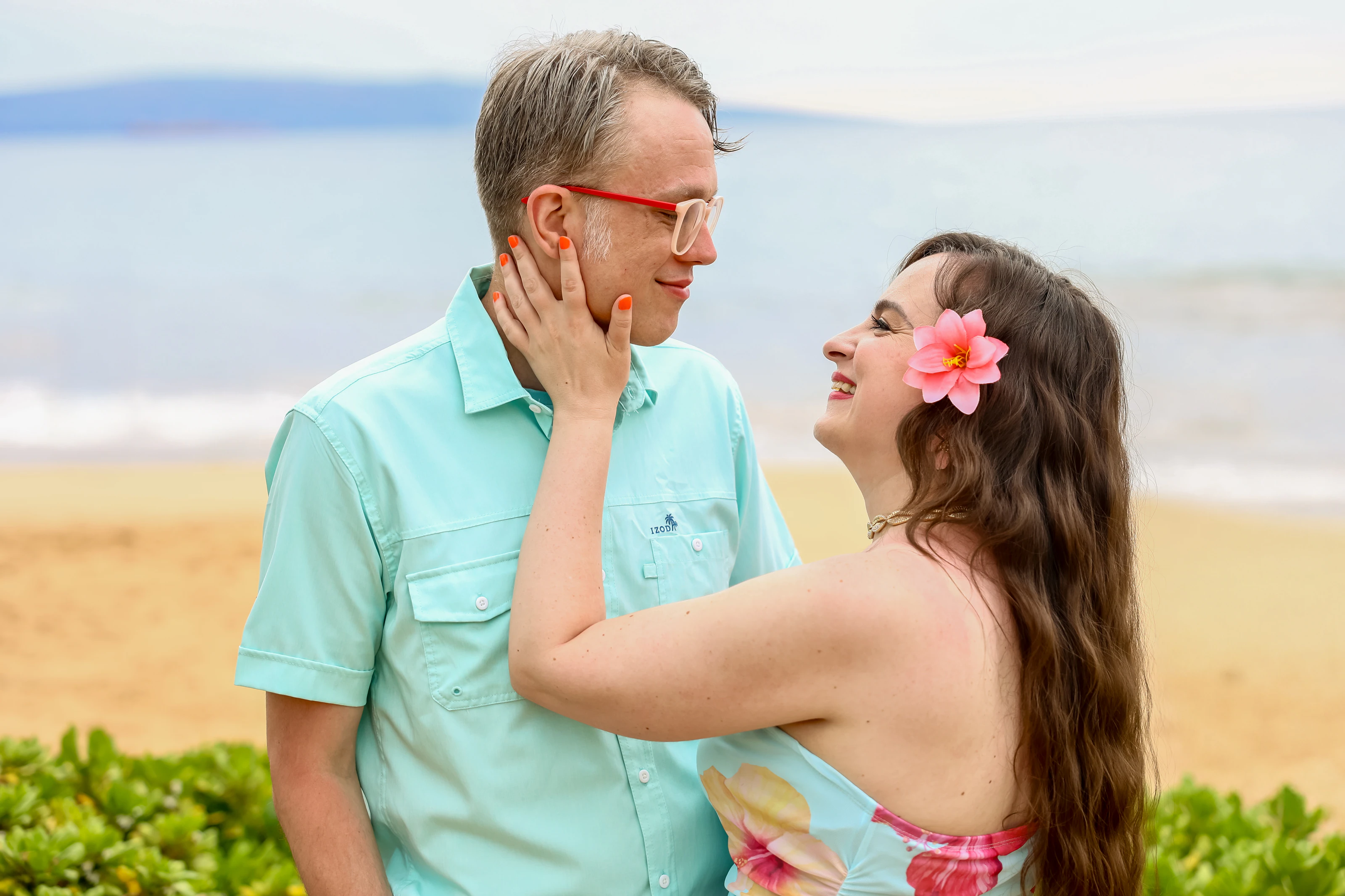 Couple sharing a playful moment near beach greenery