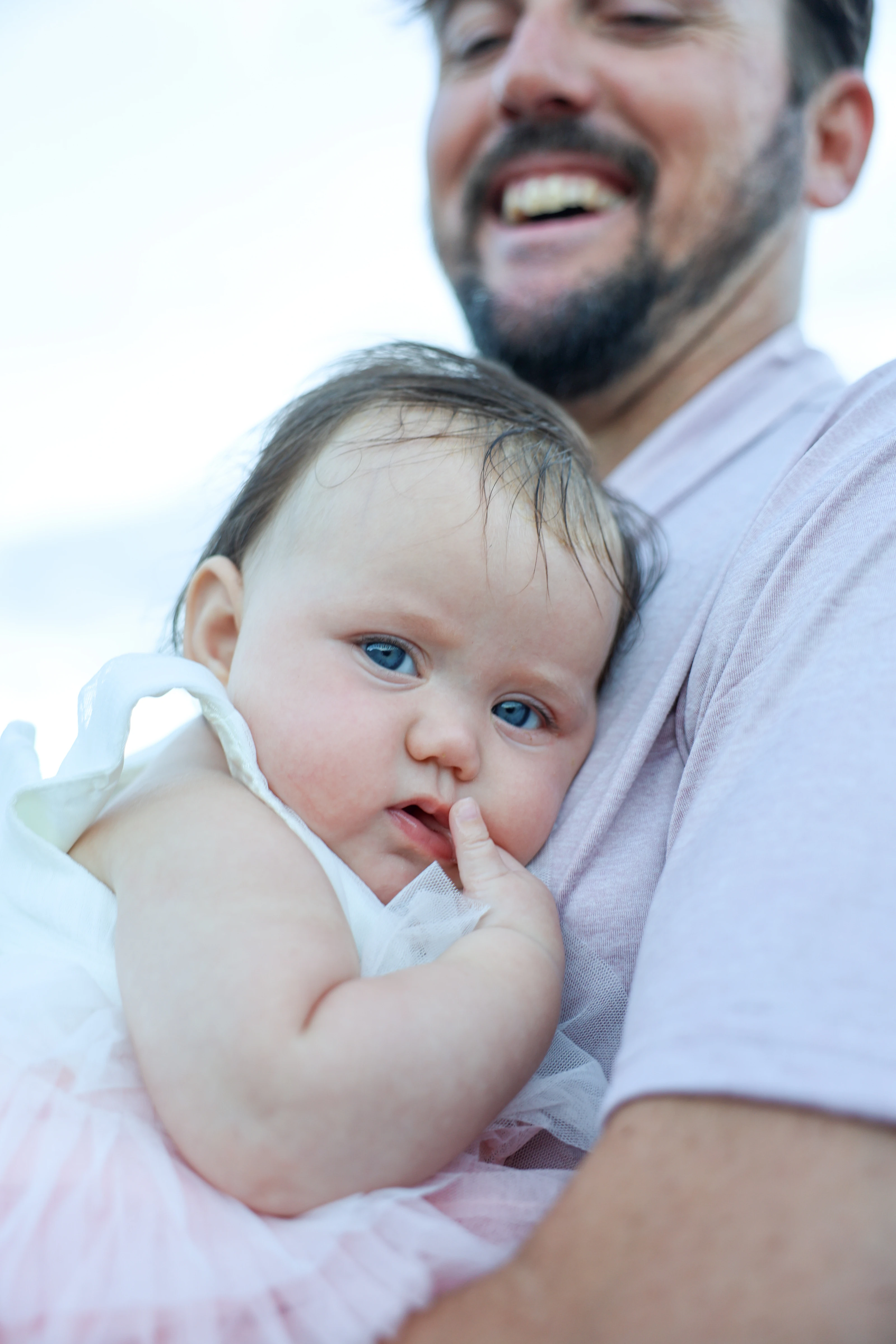 Baby held close by a smiling parent outdoors
